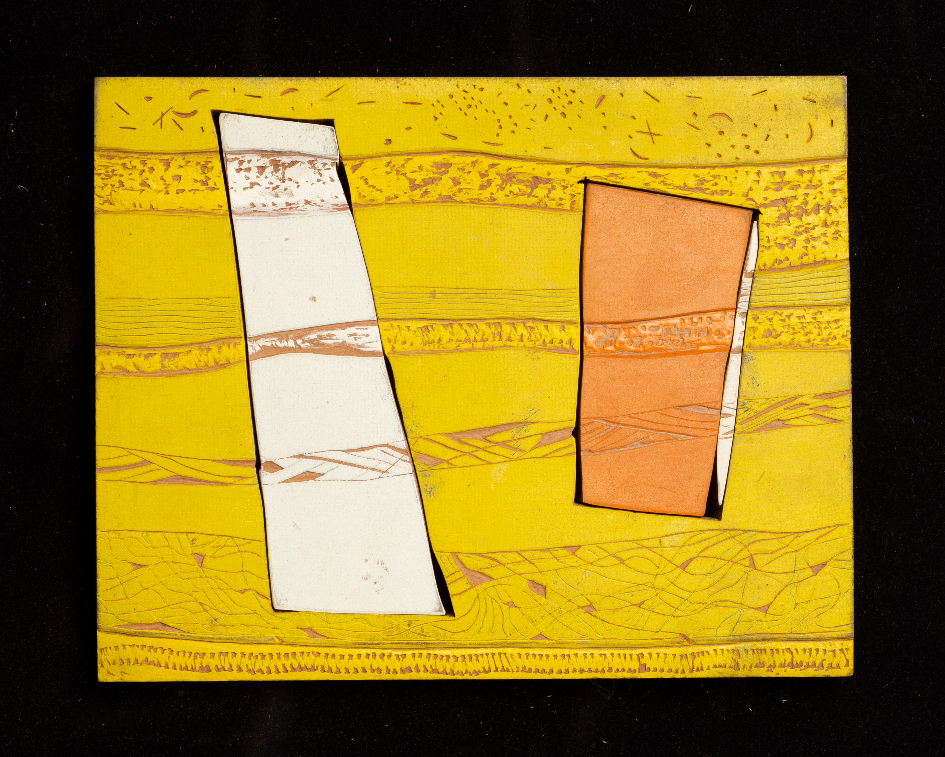 A yellow, rectangular, carved block of wood; two smaller rectangular pieces, white and orange, are inside.