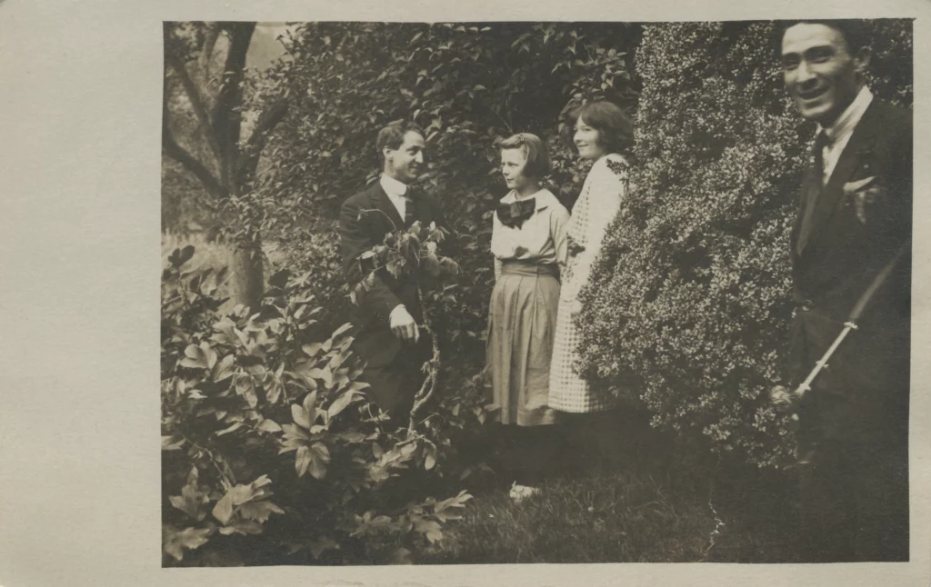 Black and white photograph from 1922 of two young girls and two young men standing amongst bushes, all with light skin tones.