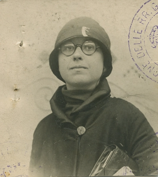 Black and white passport photo from 1920 of a young, light-skinned women wearing a coat, round glasses, and a flapper hat