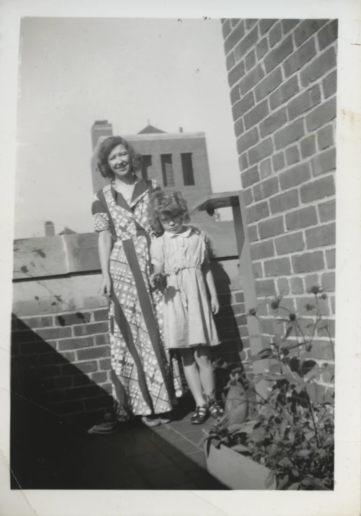 Photograph from the late 1930s of a light-skinned woman and a younger, light skinned girl on a brick building rooftop.