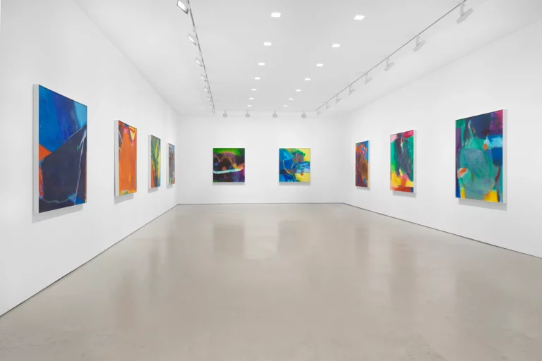 Photograph of a gallery space with 9 large, colorful, abstract paintings hanging on white walls.