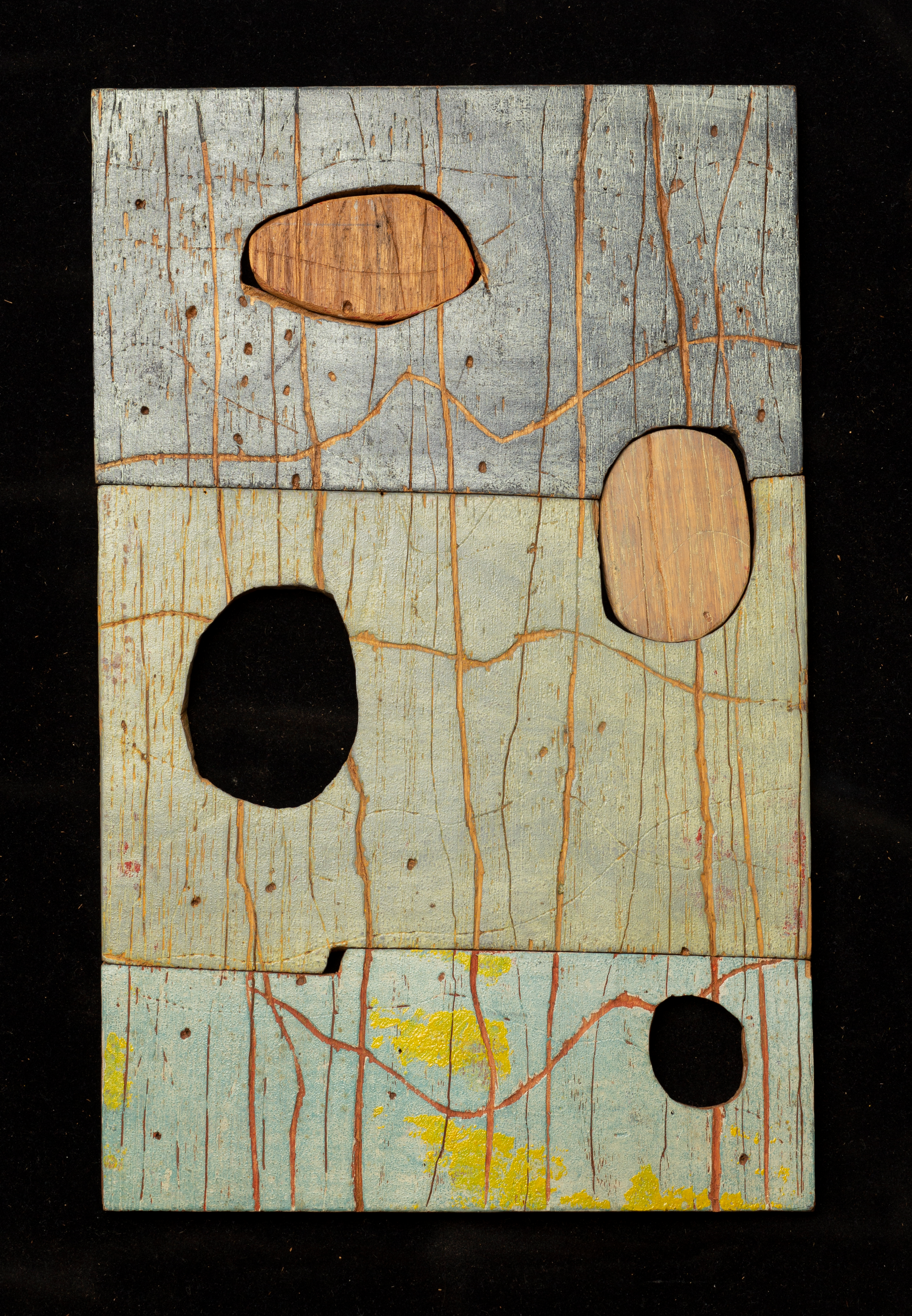 ATM-1955_OBJ_01_back Image of a grey wooden block carved with curved lines and four imperfect circles of varying size cut out.