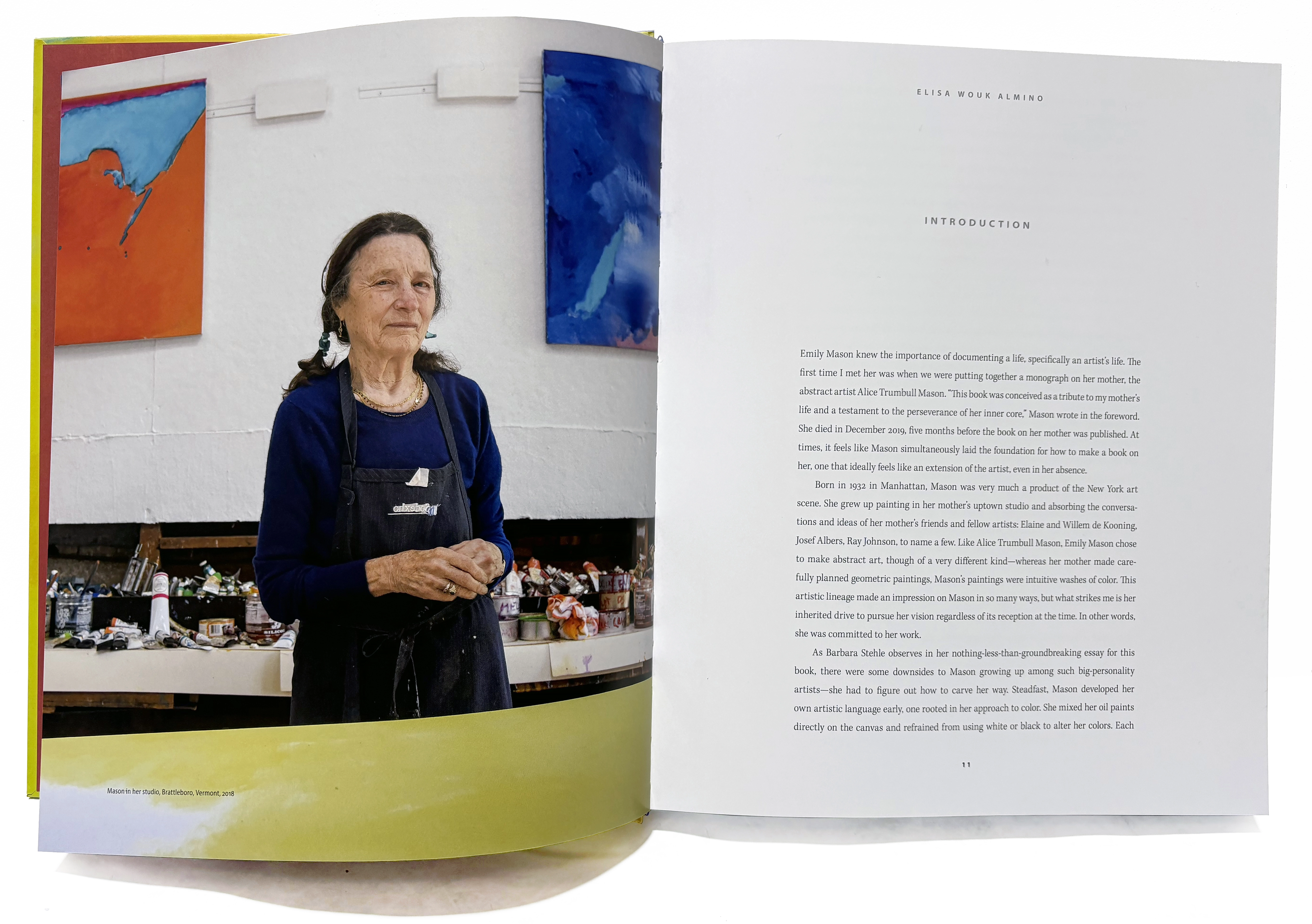 Open book spread showing a portrait of an older, light-skinned woman on the left in front of abstract paintings on the wall, and a page of text on the right.